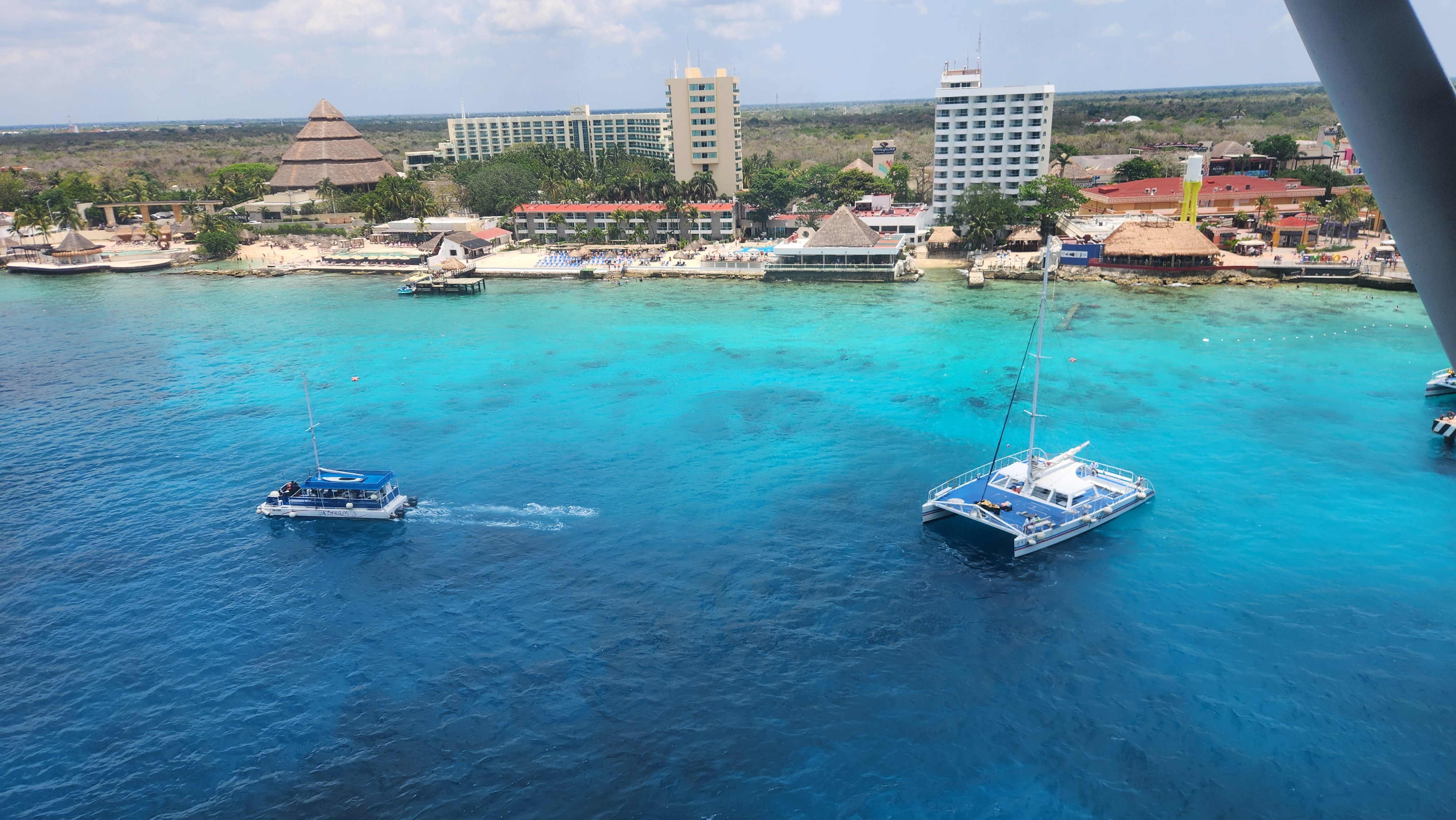 Turquoise Caribbean water with boats and a tropical resort shoreline