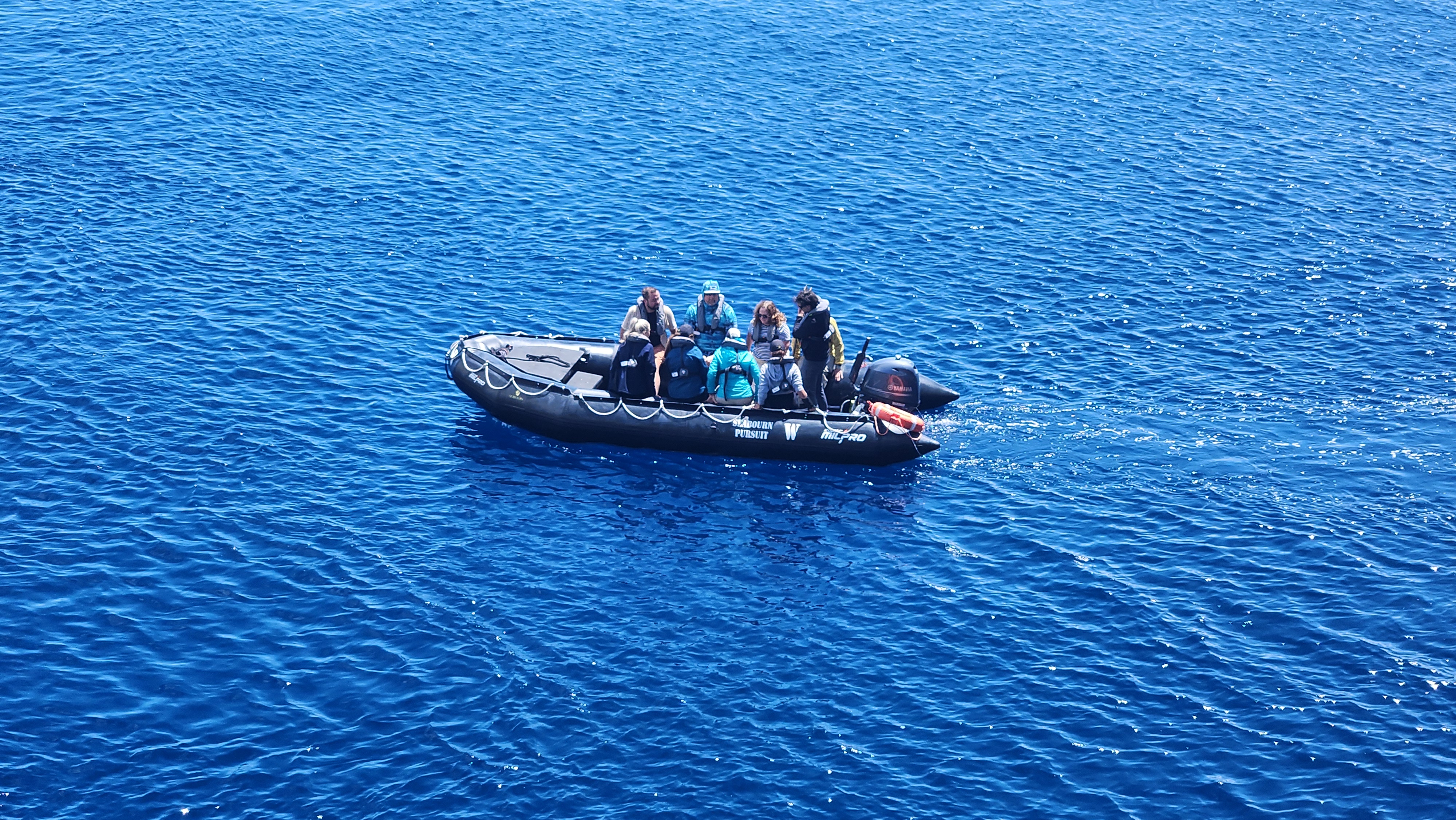Seabourn expedition guests traveling by Zodiac near a remote coastal destination.